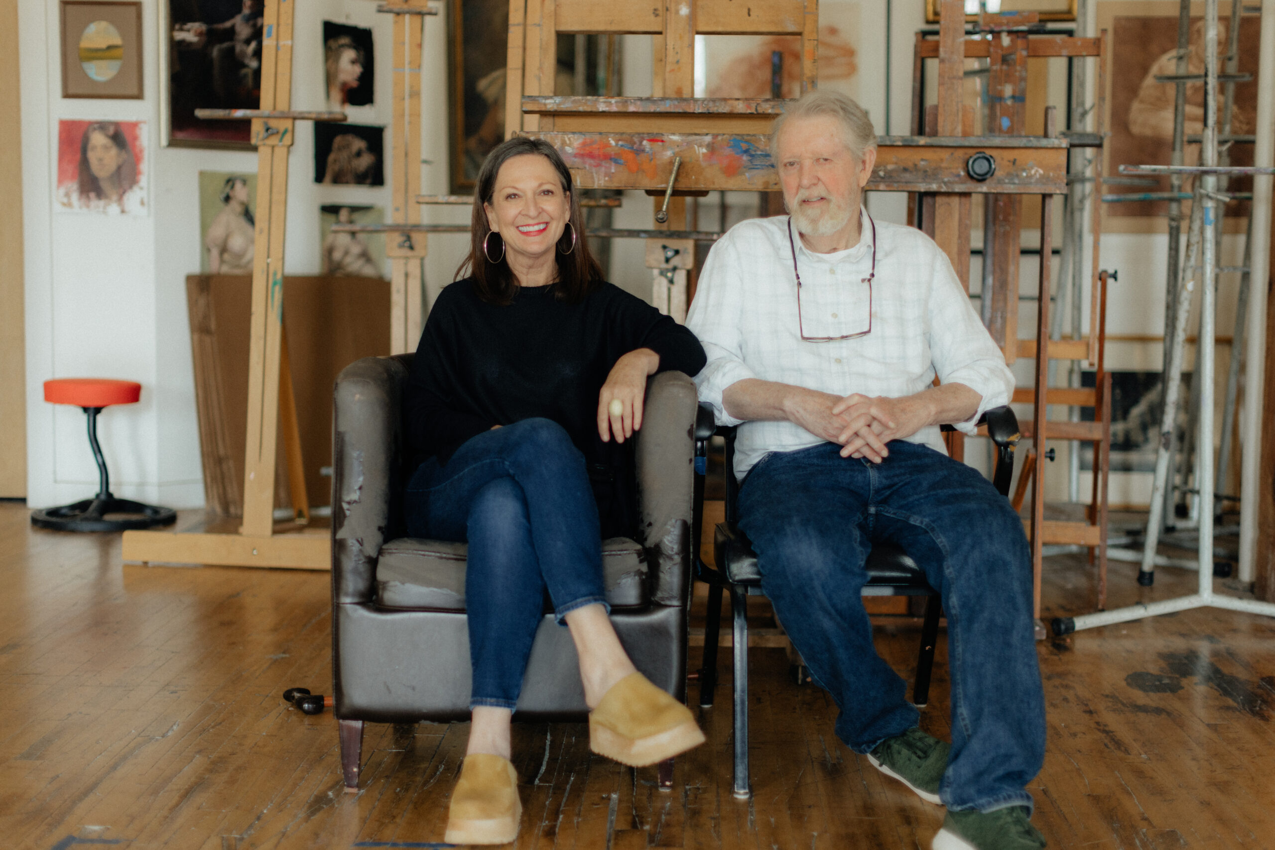 Portrait of Peggy and Stan Townsend in Townsend Atelier. The couple are seated with their artwork surrounding them.